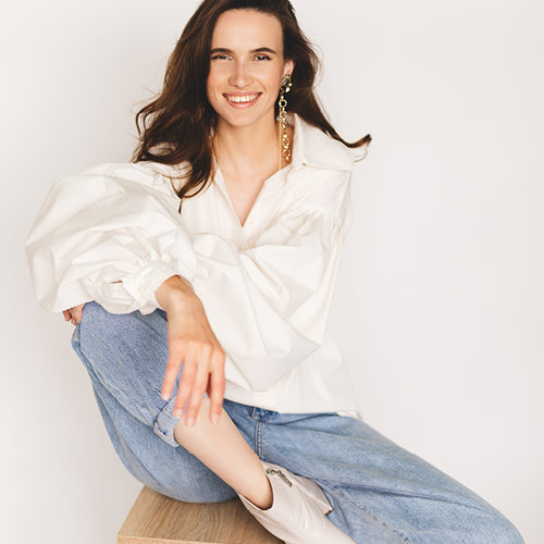 women in white button up and blue jeans smiling